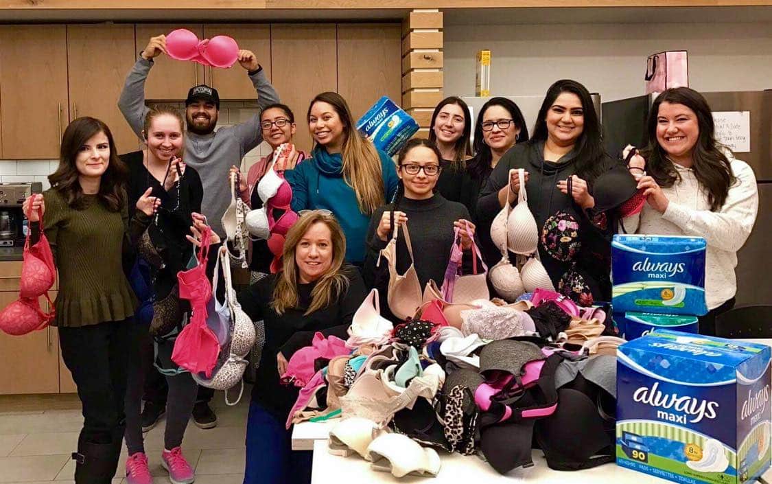 Employees of Victoria's Secret standing in an office holding different colored and styled bras